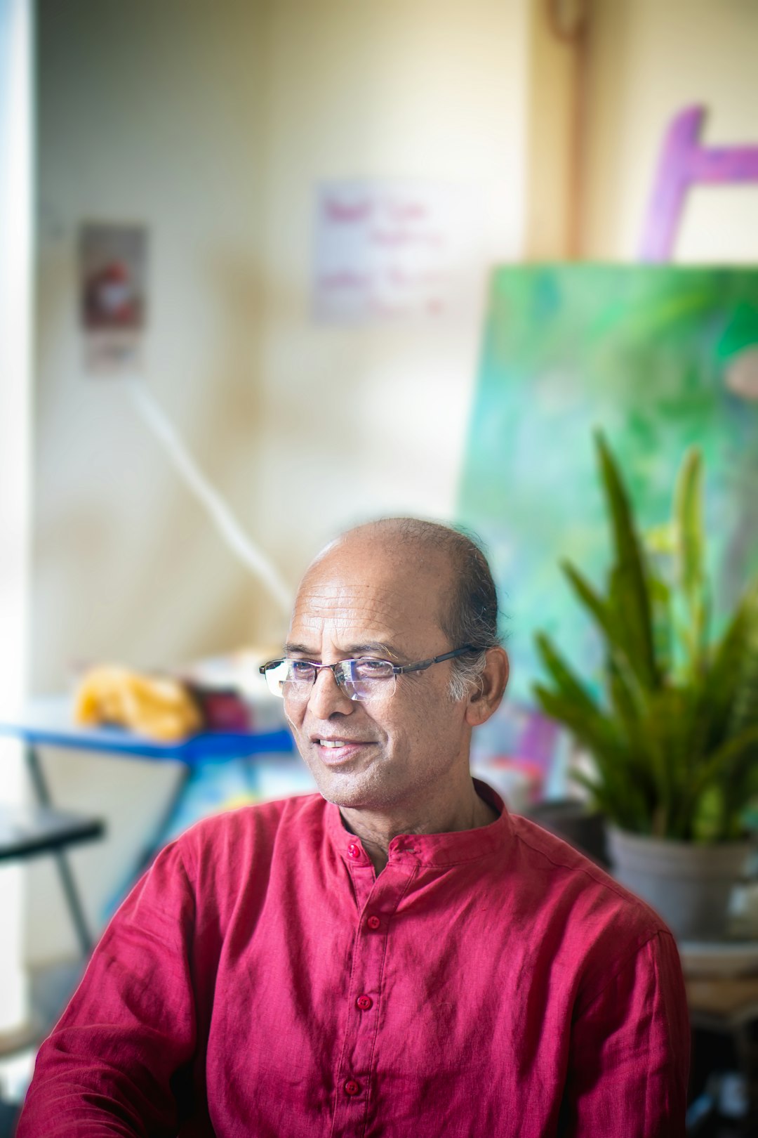 Man in red kurta with glasses smiling